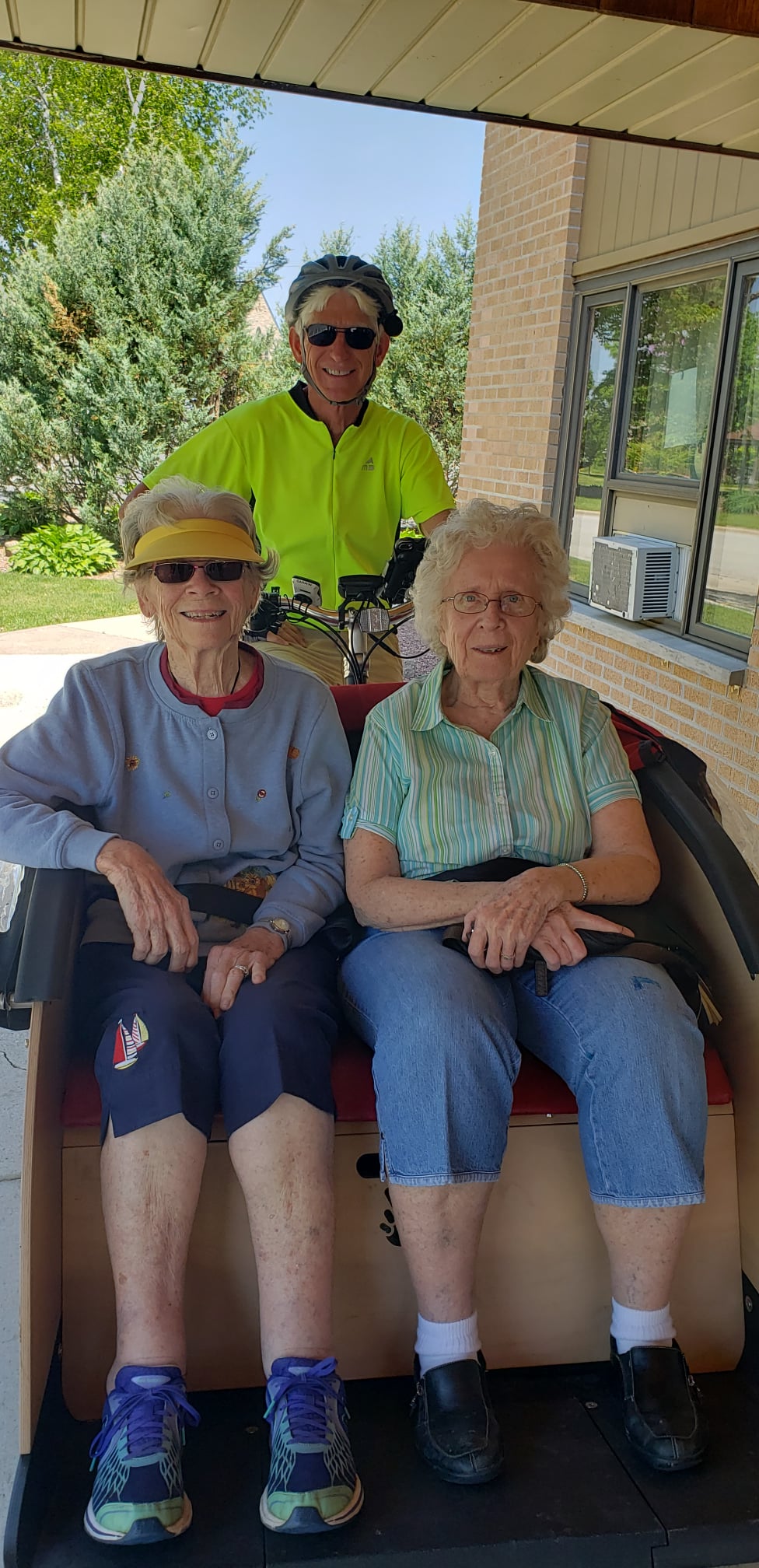 Pine Haven residents smiling with volunteer on a bicycle
