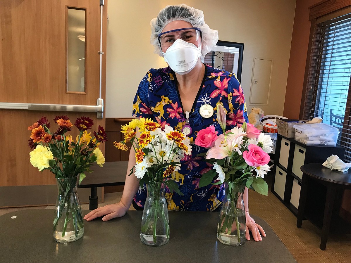 Pine Haven skilled nursing facility CNA posing with flowers at Haven Drive