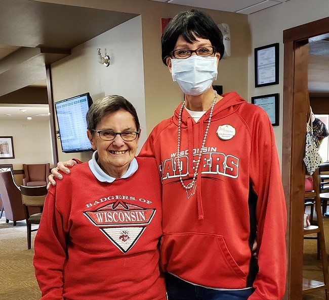 A staff member and resident wear Wisconsin Badger clothes